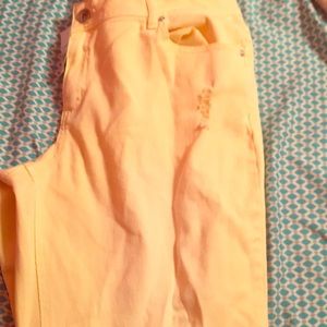 Bright yellow  jeans  with holes .